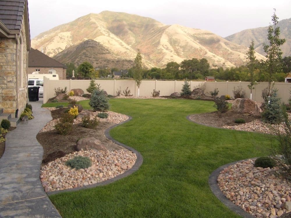 Lush green lawn with rocky landscaping and mountains in the background.