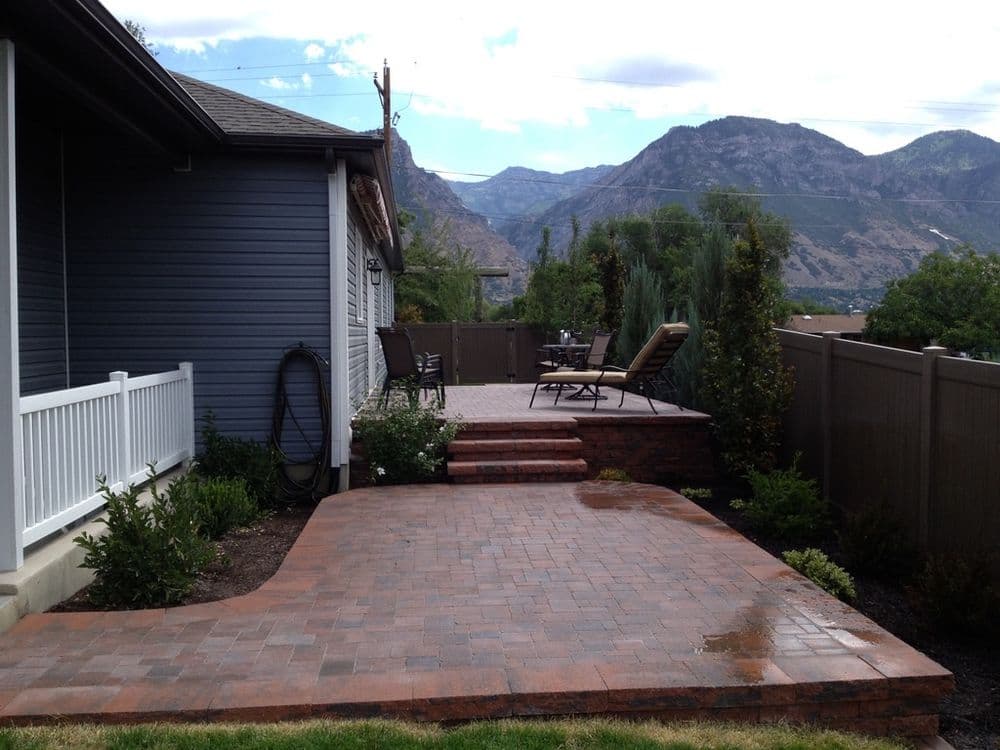 Backyard patio with stone paving, seating area, and scenic mountain views.
